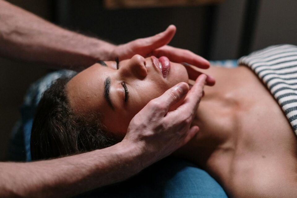 immagine di una ragazza coricata mentre le fanno un massaggio al viso 